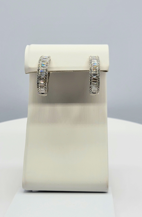 Silver hoop earrings displayed on a white jewelry stand against a light gray background