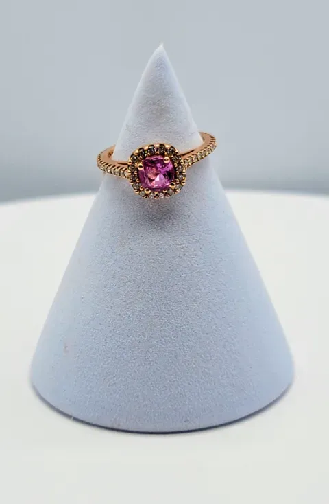 Pink gemstone ring on a gold band displayed on a white velvet cone stand.