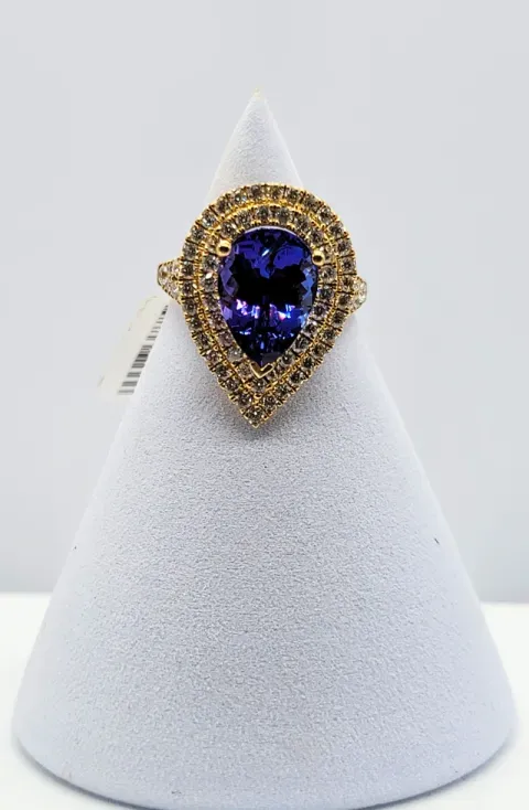 Gold and purple gemstone ring on a white display cone