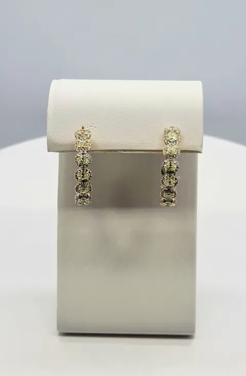 White jewelry display stand with a pair of dangling gold-toned earrings
