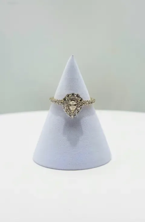 Gold ornate ring on a light blue cone-shaped display stand against a pale background