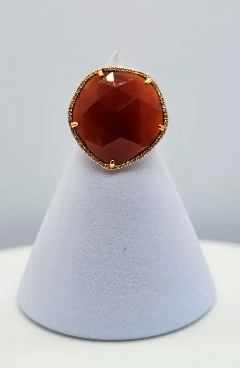 Amber faceted ring on a white display stand