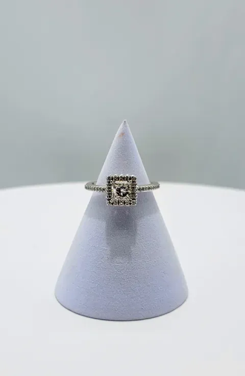 Diamond-studded square ring on a gray display cone against a light background