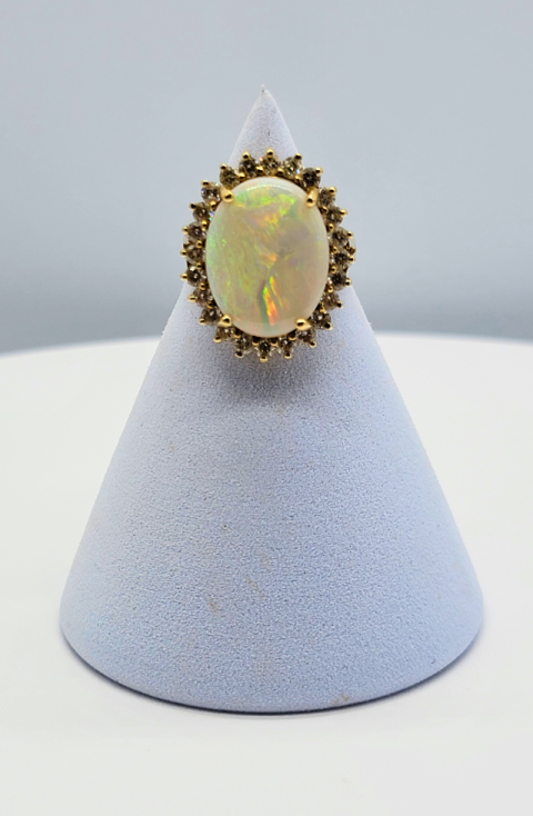 Oval opal ring with gold halo setting displayed on a white cone stand
