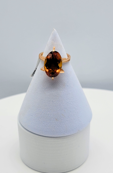 Amber gemstone ring on a white display stand against a gray background