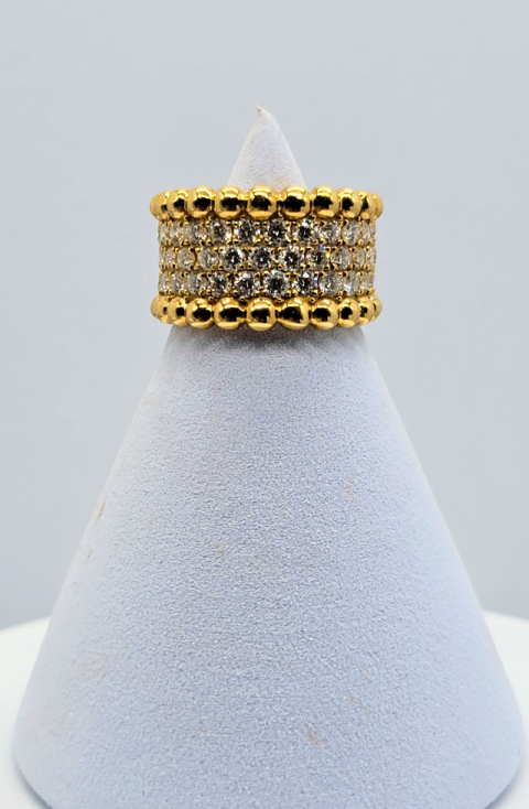 Gold and black beaded ring stacked on a white display cone