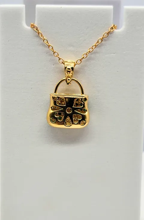 Gold pendant necklace with a small black floral charm on a display card