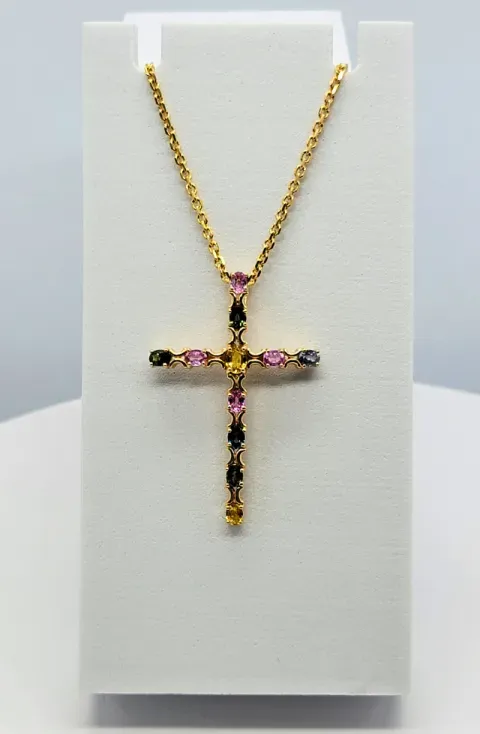 Gold and black jeweled cross pendant necklace on a white display stand