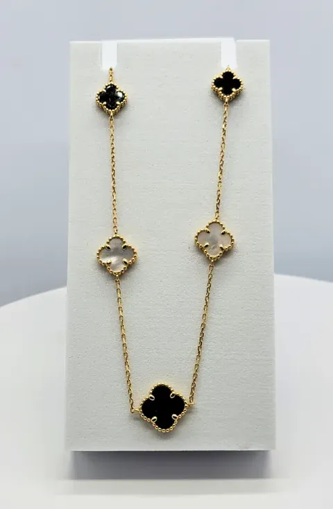 Gold-and-black clover necklace with matching clover accents displayed on a white stand