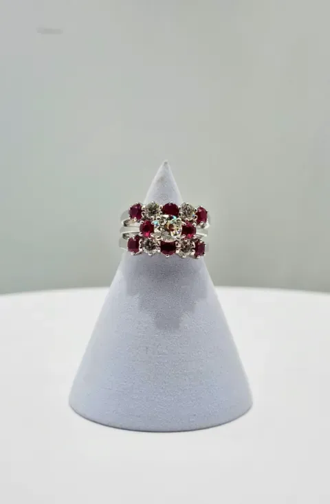 Red gemstone ring on a white cone display stand against a plain background