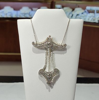 Silver chain necklace with an ornate pendant displayed on a white jewelry bust