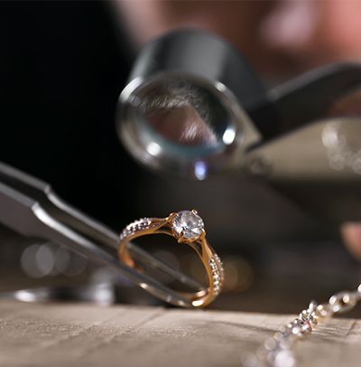 Diamond ring under jeweler's loupe on a workbench