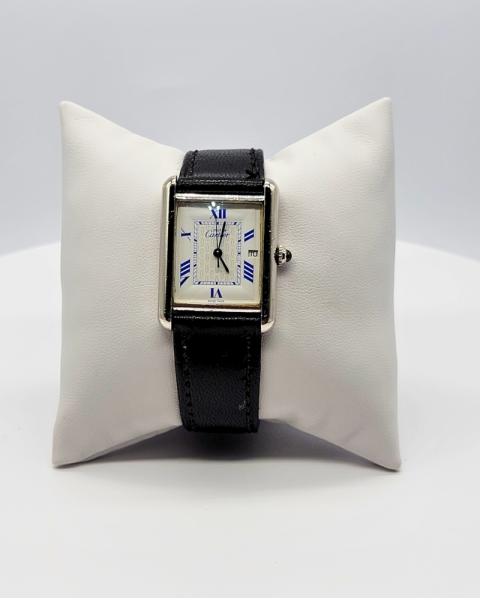 Rectangular wristwatch with black leather strap displayed on a white cushion