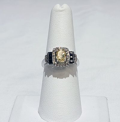 Gold and black gemstone ring displayed on a white cone stand