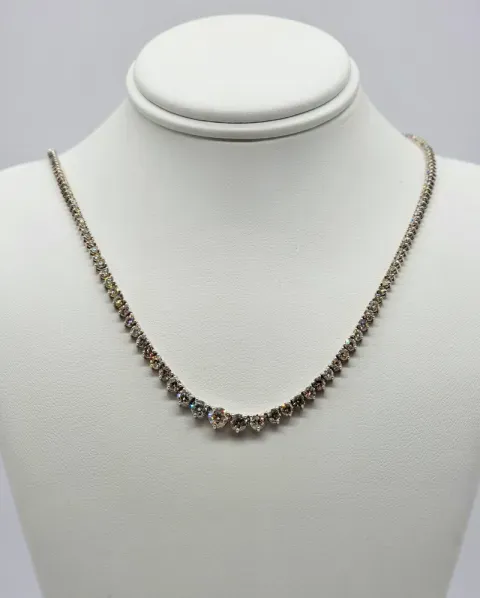 Gold necklace with clustered gemstone accents displayed on a white jewelry bust.