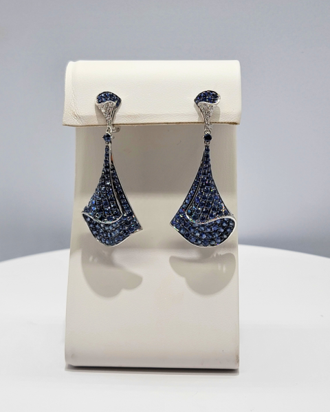 Blue teardrop earrings displayed on a white jewelry stand