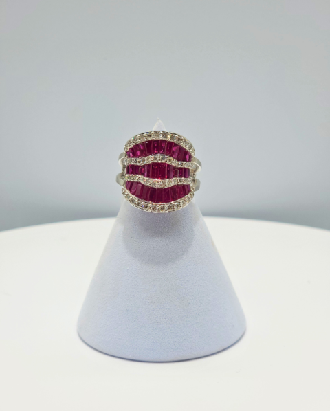 Gold ring with red gemstones on a white display stand.