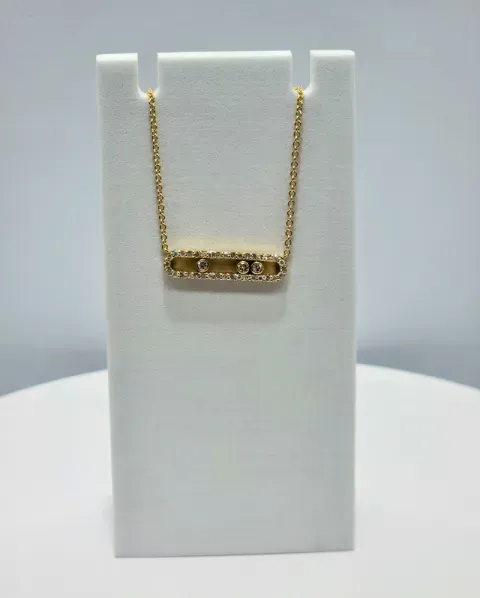 Gold chain necklace with a small horizontal bar pendant on a white display stand