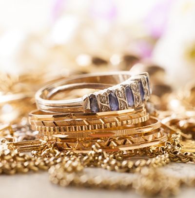 Stacked gold bracelets with a silver ring set with blue stones on a soft, blurred background