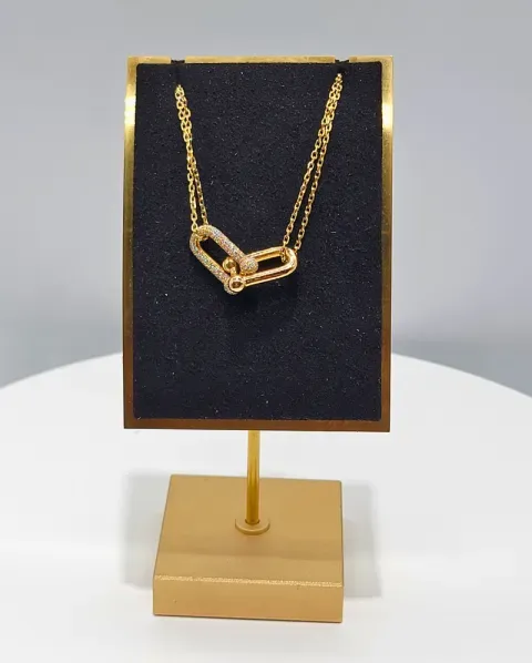 Gold chain necklace displayed on a black velvet jewelry stand with a gold base