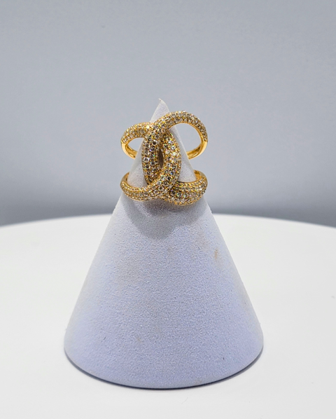 Gold ring ornament on a lavender cone display against a gray background