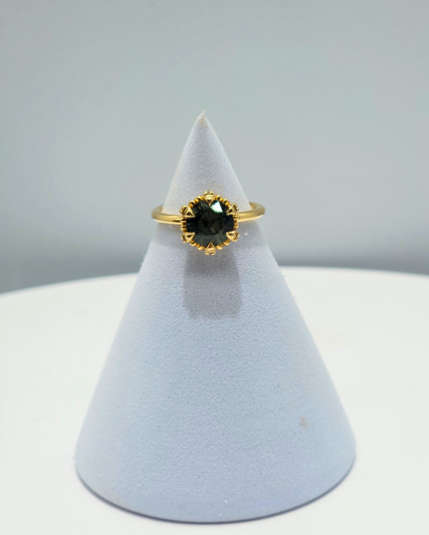Gold ring with dark green gemstone on a white display cone