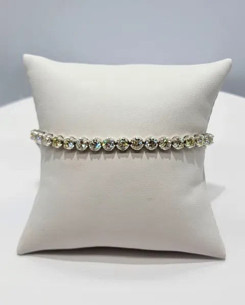White pillow displaying a sparkling rhinestone bracelet on a light gray background