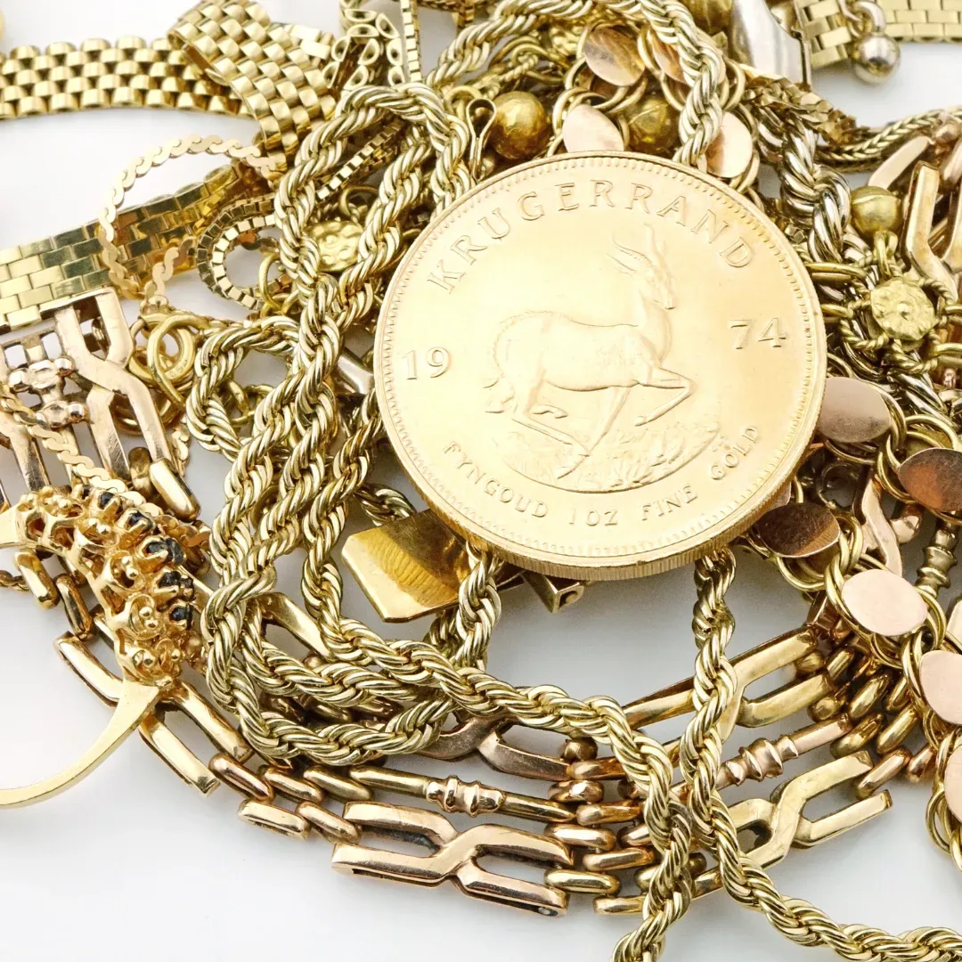 Assorted gold chains and coins piled together on a white background.