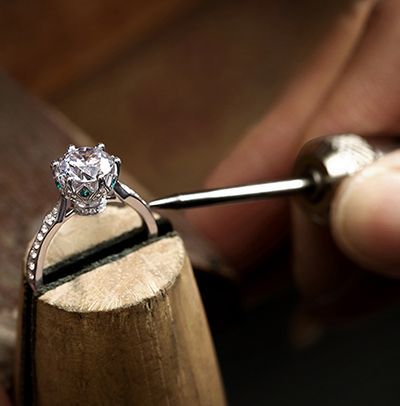 Diamond ring being adjusted on a jeweler’s bench with a tool attached to a wooden holder