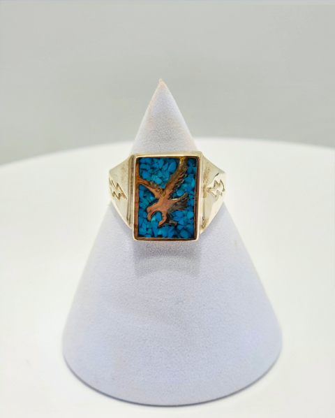 Gold ring with turquoise inlay and bird design on a white display cone