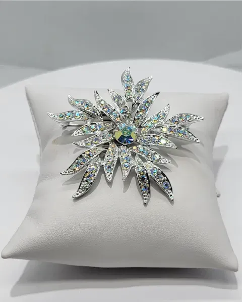 Crystal snowflake brooch with iridescent stones on a white satin pillow