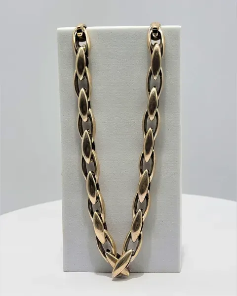 Gold chain necklace displayed on a gray bust stand
