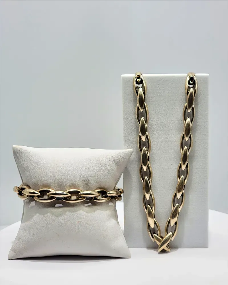 Gold chain necklace draped over a white pillow and displayed on a white stand