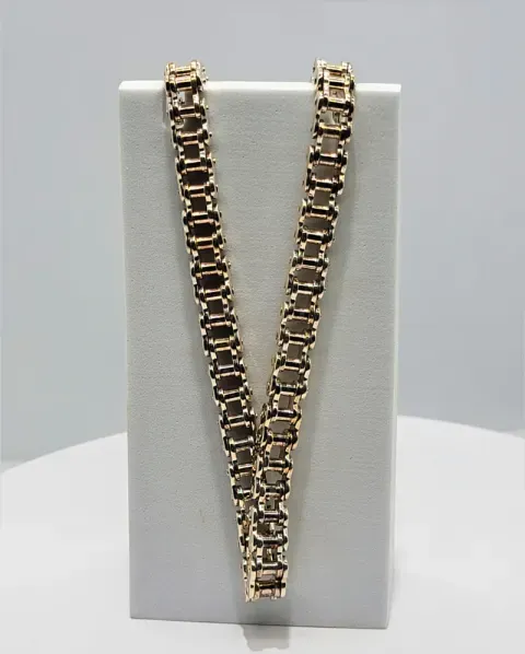 Gold chain necklace displayed on a white jewelry bust against a gray background
