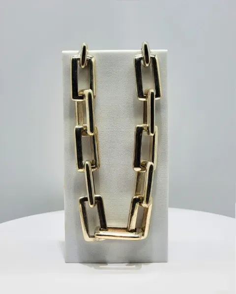 Gold chain necklace displayed on a white stand against a gray background