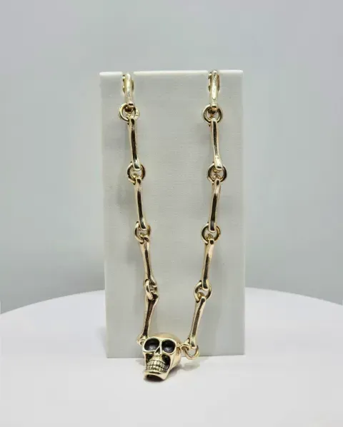 Gold skull pendant necklace on a white display stand
