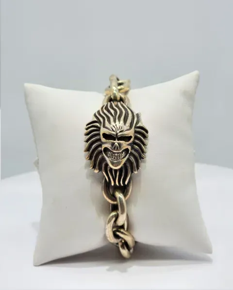 White pillow with a gold lion-head chain ornament on a light gray background