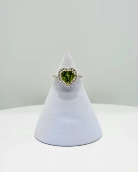 Heart-shaped green gemstone ring displayed on a white cone stand
