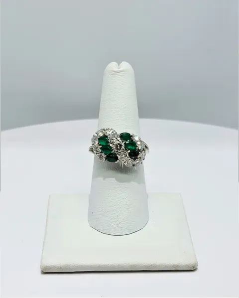 Green gemstone ring on a white display stand against a plain gray background