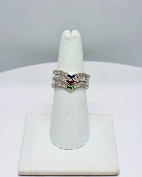 Silver chevron ring with red, blue, and green stones on a white display stand
