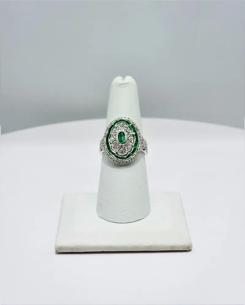 Green gemstone ring on a white display stand against a light gray background