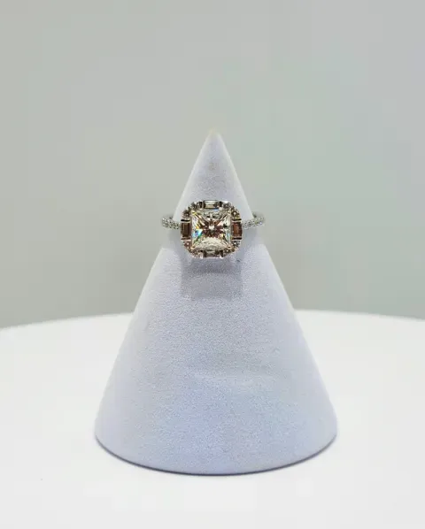 Silver ring with a square gemstone displayed on a white cone stand