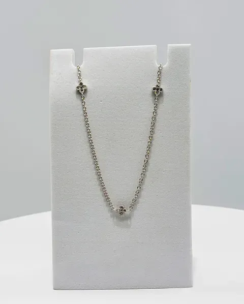 Silver necklace with small pendant displayed on a white jewelry stand