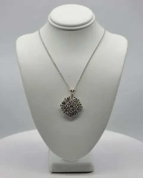 Silver necklace with a round pendant displayed on a white jewelry bust.