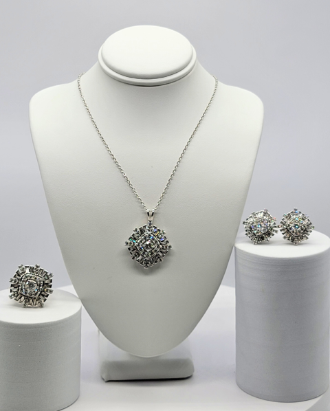Jewelry display with silver necklace and matching earrings on white bust and pedestals