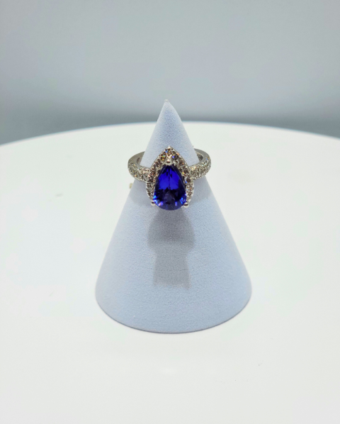 Blue gemstone ring displayed on a white cone stand against a light background