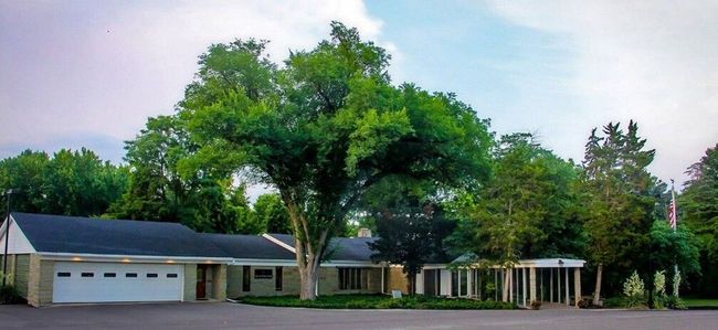 Building with columns and a garage, trees, and sky.