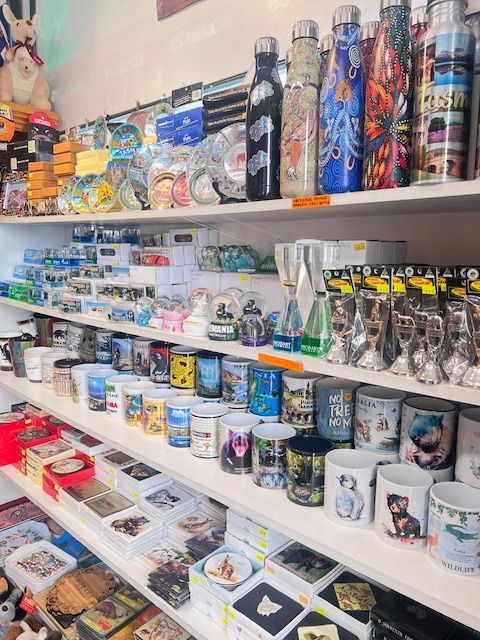 Shelves of colorful mugs, tumblers, and gift items in a shop display