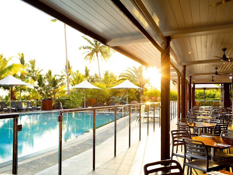 A Restaurant with Tables and Chairs Next to A Swimming Pool — North Queensland Glass & Glazing In Cannonvale, QLD