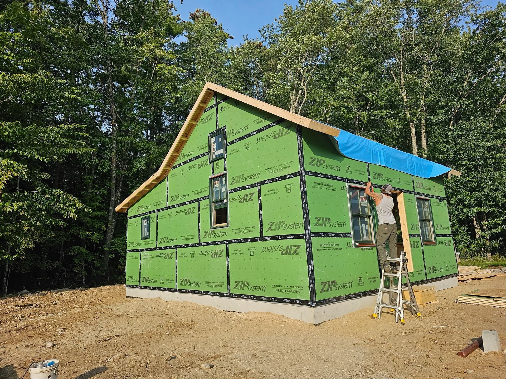 a man on a ladder working on a house with zipsystem sheathing